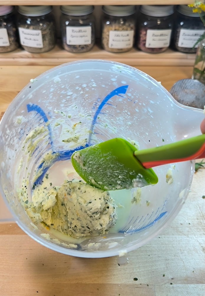 Fein gehackte Wildkräuter werden in einer Schüssel unter die weiche Butter gerührt