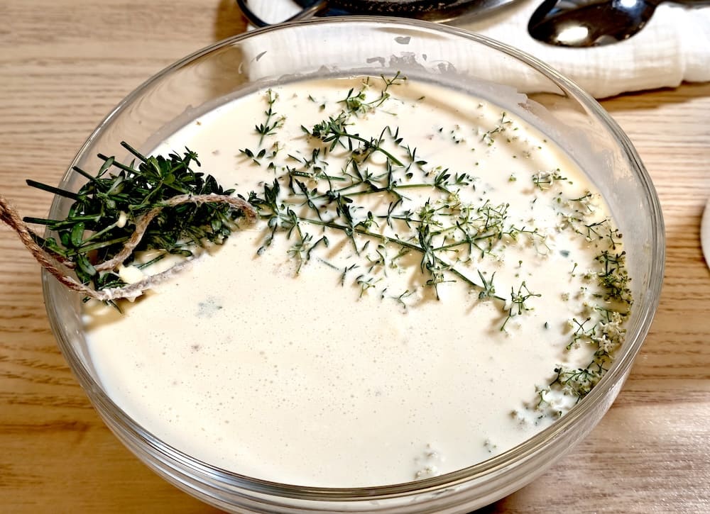 Milch mit eingelegtem Labkraut-Strauß in einer Glasschüssel Milch mit eingelegtem Labkraut-Strauß in einer Glasschüssel