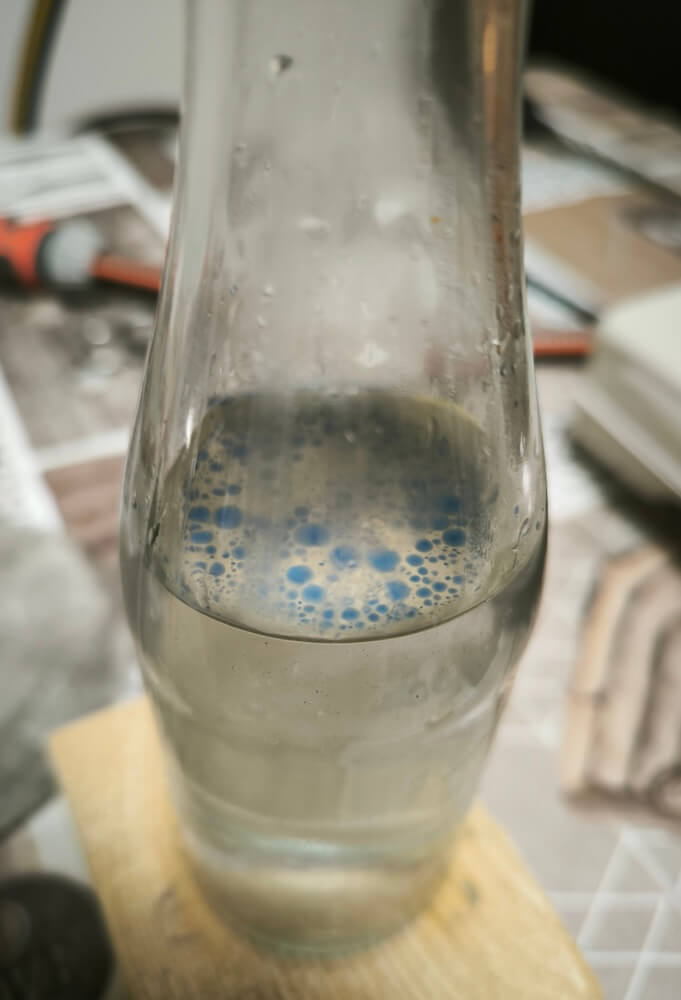 Blaue Tropfen ätherisches Schafgarbenöl setzen sich auf dem Hydrolat ab