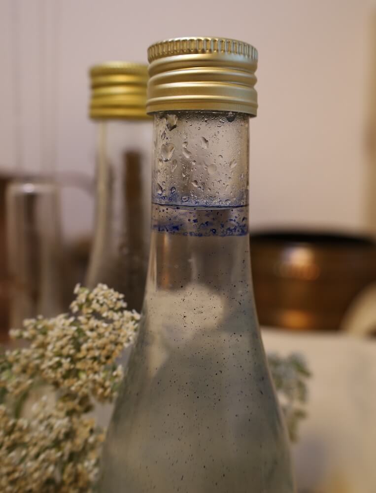 Abgefülltes Schafgarbenhydrolat mit blauer Ölschicht in verschlossenen Flaschen